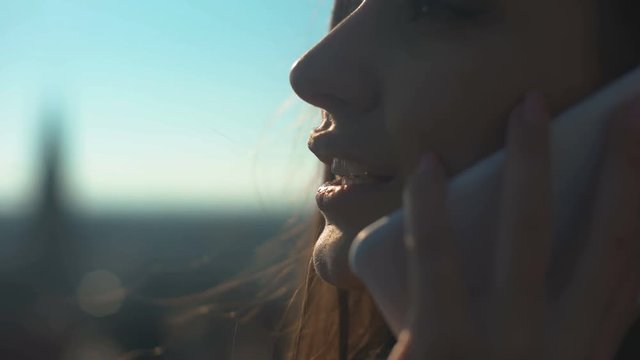 Pretty smiling lady chatting on phone with friend standing on skydeck connection