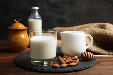  Milk in a glass cup, milk jug, honey and almond nuts