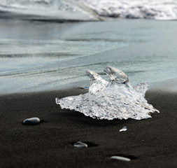 Piece of ice on black sand