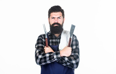 Roasting and grilling food. Man hold cooking utensils barbecue. Tools for roasting meat outdoors. Picnic and barbecue. Cooking meat in park. Masculine hobby. Bearded hipster wear apron for barbecue