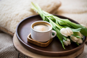 Obraz na płótnie Canvas Coffee cup with tulips bouquet in wooden plate, home cozy interior details