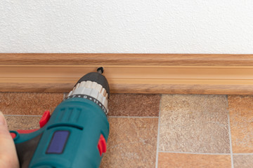 Installation of plastic floor plinth. Interior details.