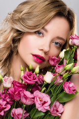 beautiful blonde woman posing with spring Eustoma flowers bouquet