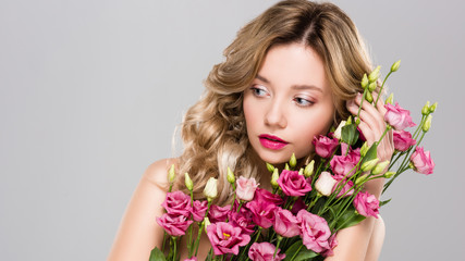Fototapeta premium naked attractive blonde woman posing with spring Eustoma flowers bouquet isolated on grey