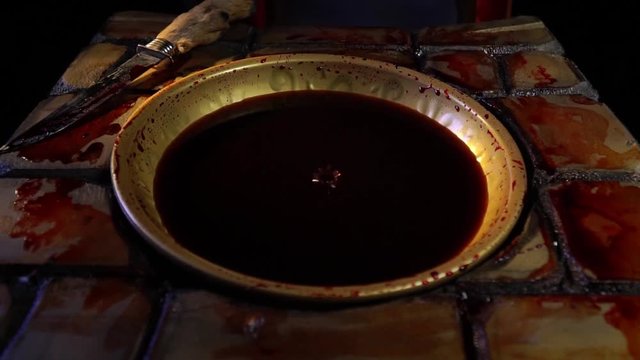 Close up of the blood dripping into the golden bowl, bloody dagger near it, ritual place