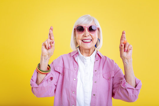 Stylish modern retired woman with bright manicure having fingers crossed