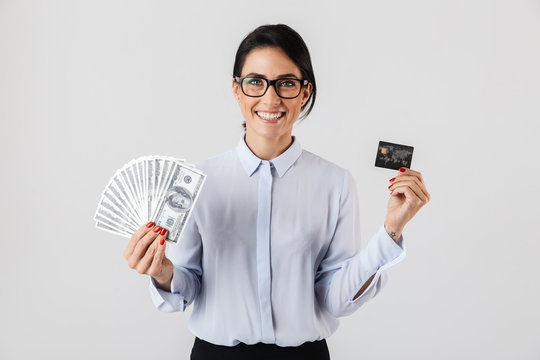 Image of young office woman wearing eyeglasses holding bunch of money and credit card, isolated over white background