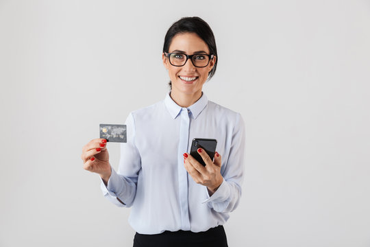Image of smart office woman wearing eyeglasses holding mobile phone and credit card, isolated over white background