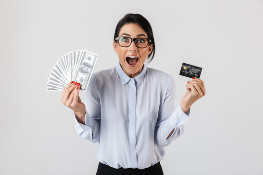 Image of happy office woman wearing eyeglasses holding bunch of money and credit card, isolated over white background
