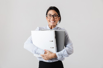 Photo of successful female worker wearing eyeglasses holding paper folders in the office, isolated over white background