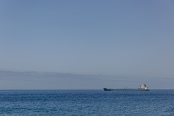 Fototapeta na wymiar View of a huge distant ship in a calm sea with a clear sky