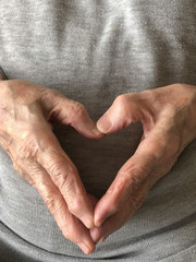 wrinkled hands of a senior person, making heart shape