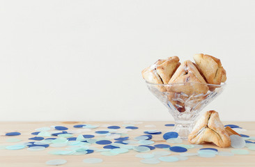 Purim celebration concept (jewish carnival holiday). Traditional hamantaschen cookies over wooden table