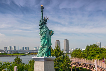 Replicas of the Statue of Liberty with cityscape background at Odaiba Park in Tokyo, Japan.