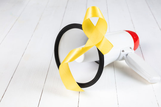 Yellow ribbon symbolic color for Sarcoma Bone cancer awareness and suicide prevention on aged wood with megaphone. The cancer, health, help, care, support, hope, illness, healthcare concept