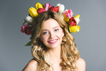 Naklejka premium happy girl with wreath of flowers on hair isolated on grey