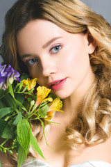 Naklejka premium attractive blonde young woman with flowers looking at camera