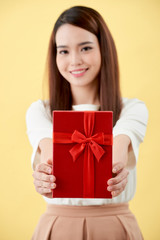 Portrait of a happy pretty asian woman holding present box while standing