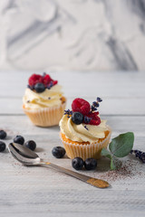Sweet dessert cupcakes with fruits on the white wooden background