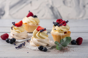 Sweet dessert cupcakes with fruits on the white wooden background