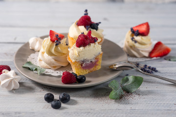 Sweet dessert cupcakes with fruits on the white wooden background