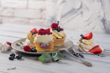 Sweet dessert cupcakes with fruits on the white wooden background