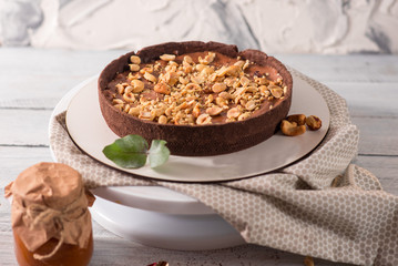 Cocolate tart with peanuts and caramel on the white wooden background
