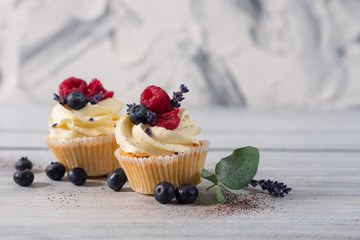 Sweet dessert cupcakes with fruits on the white wooden background