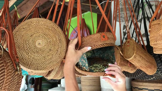 Woman choosing rattan eco bags in the art shop on Bali island, Indonesia. Woman stylish eco bag.