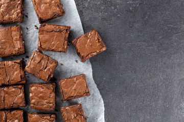 Chocolate brownie on paper on dark grey base top view flat lay