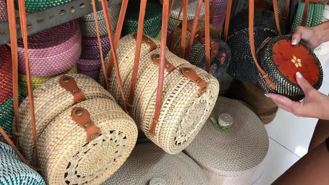 Woman choosing rattan eco bags in the art shop on Bali island, Indonesia. Woman stylish eco bag.