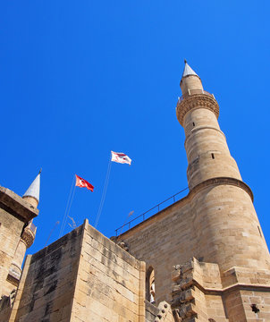 turkish and north cyprus flying over minarets of Selimiye Mosque formerly the cathedral of Saint Sophia in nicosia cyprus against a blue sky