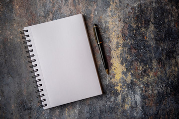 Empty notebook and pen on a stone marble background, with copy space