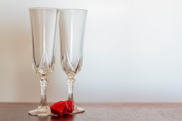Two champagne glasses and two chocolate heart candies. Valentines day concept