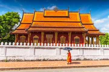 A Buddhist monk walks by the Wat Sen Temple in Luang Prabang, Laos. © GISTEL