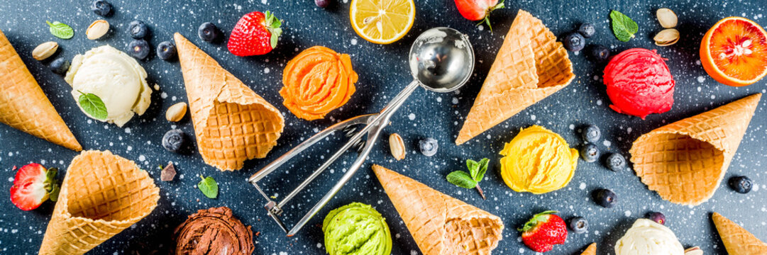 Colorful fruit and berry, nut, chocolate and vanilla ice cream, with waffle ice-cream cones, with fresh fruit and berries, top view copy space dark blue background banner