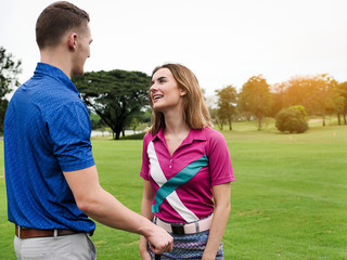 Golfer couple talking together at green field, lifestyle concept