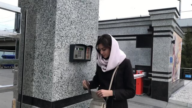 brunette woman calls into the intercom on the street, autumn day in warm clothes