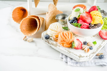 Colorful fruit and berry, nut, chocolate and vanilla ice cream, with waffle ice-cream cones, with...