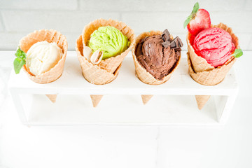 Colorful fruit and berry, nut, chocolate and vanilla ice cream, with waffle ice-cream cones, with fresh fruit and berries, top view copy space white marble background