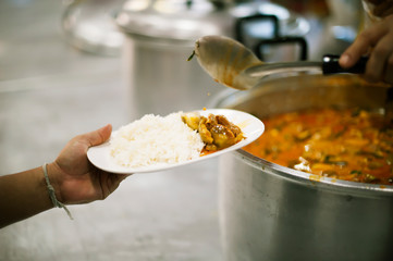 The poor people bring a container to scoop food to eat and relieve hunger and bring home.