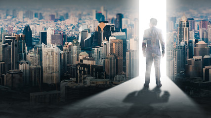 The double exposure image of the businessman standing front of the door is opening during sunrise overlay with cityscape image. The concept of modern life, business, city life and future.