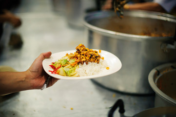 The poor people bring a container to scoop food to eat and relieve hunger and bring home.