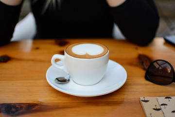 A young blond female enjoys a spring with a tasty coffee in a white cup in a cafe garden. A blond girl makes a coffee break at a nearby restaurant. A woman is waiting for her boyfriend to join her in 