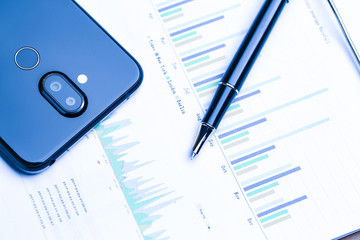 pen,cellphone and business statistics on wooden table