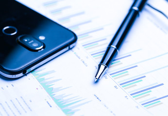 pen,cellphone and business statistics on wooden table