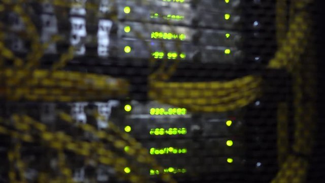 Working data servers with flashing LED lights. Blurred background. Yellow cable. Datacenter in blue light.
