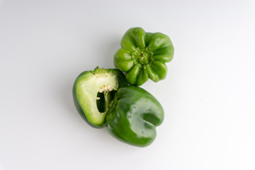Fresh green bell peppers (capsicum) on a white background. Selective focus and crop fragment
