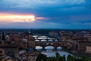 River Arno with bridge Ponte Vecchio in the evening view from Piazzale Michelangelo. Dramatic sunset dark blue sky. Amazing beautiful sunset. Florence, Italy.