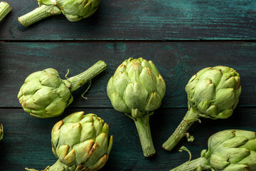 Many globe artichokes on a wooden background, shot from above with a place for text